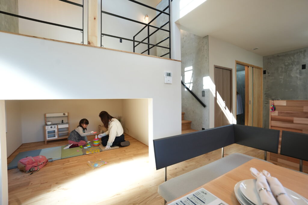 スキップフロア下の秘密基地のようなキッズスペースで、母親と子供が遊んでいる風景