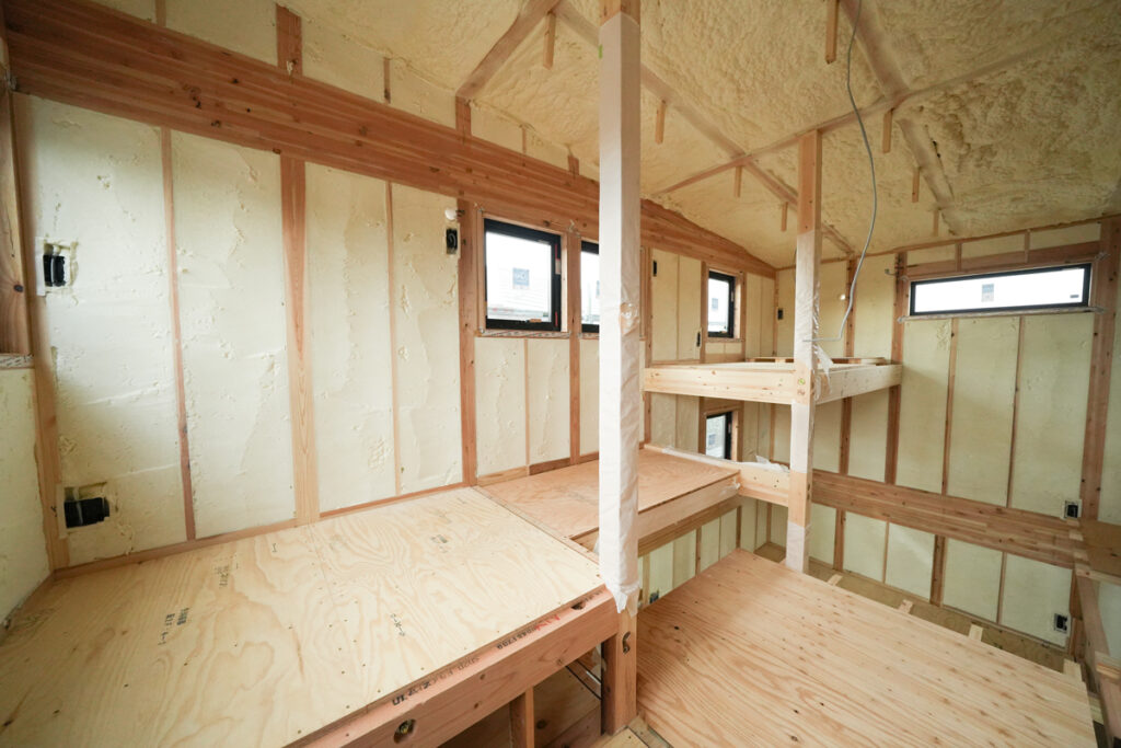 住宅建築現場の内部で、壁や屋根裏に隙間なく吹き付けられた発泡ウレタン断熱材の様子