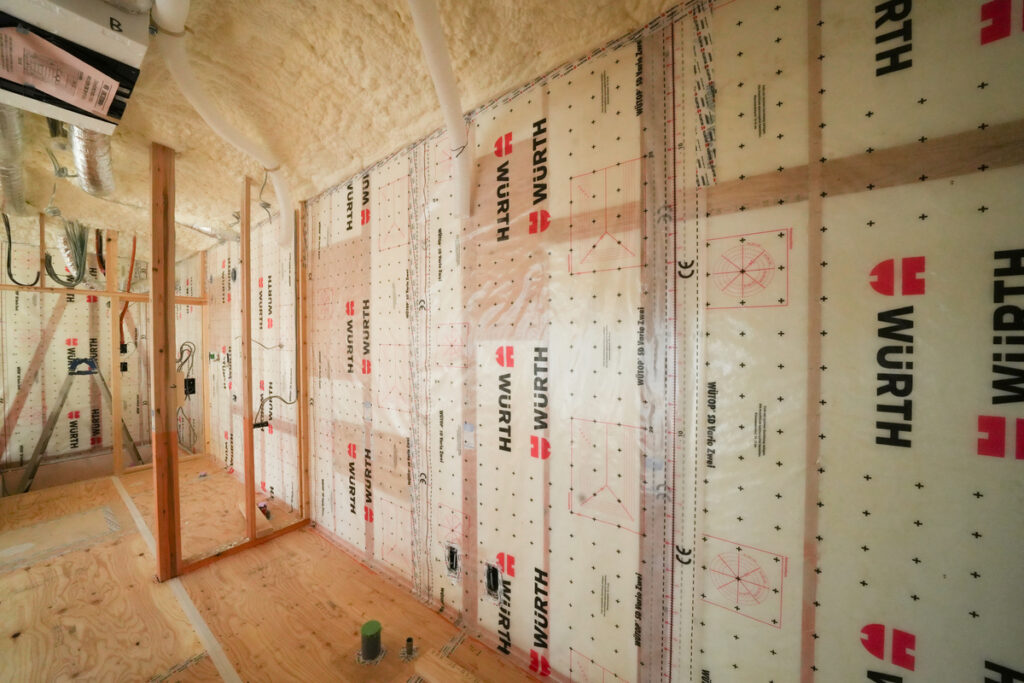 住宅建築現場で壁一面に隙間なく施工された気密シートと断熱材の様子