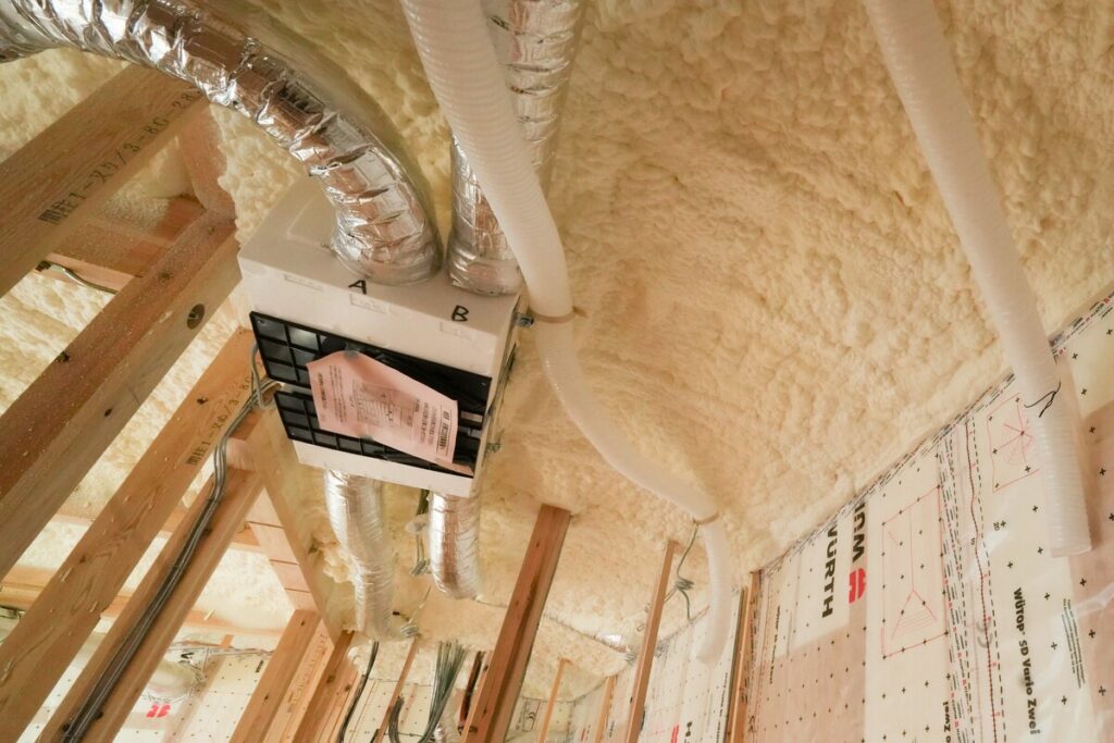 天井裏の複雑な配管周りまで発泡ウレタン断熱材が隙間なく吹き付けられた施工風景
