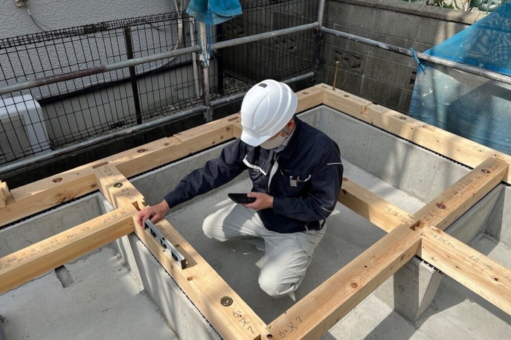 基礎の上に組まれた土台の水平精度をデジタル水平器で測定する様子。家の傾きを防ぐため、1棟ごとに精密な検査を実施する。