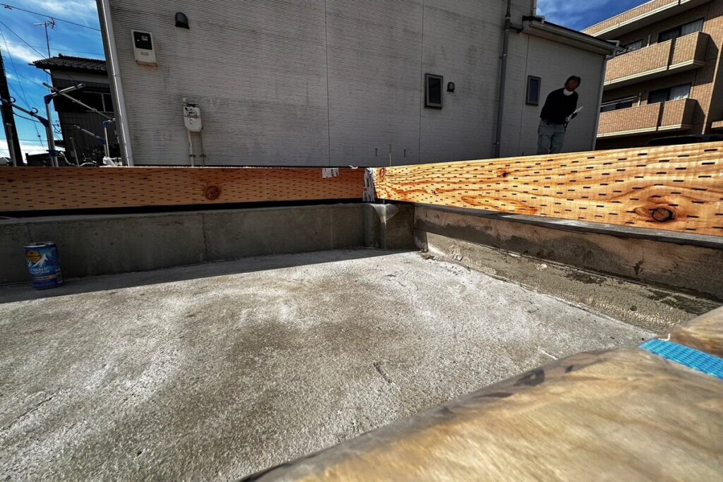 コンクリート基礎の上に、防蟻・防腐処理が施された土台を設置した状態。建物の荷重を支える重要な構造部の施工風景。